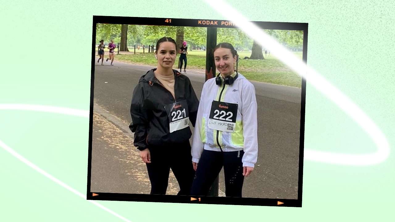 two women standing in a park while wearing racing bibs