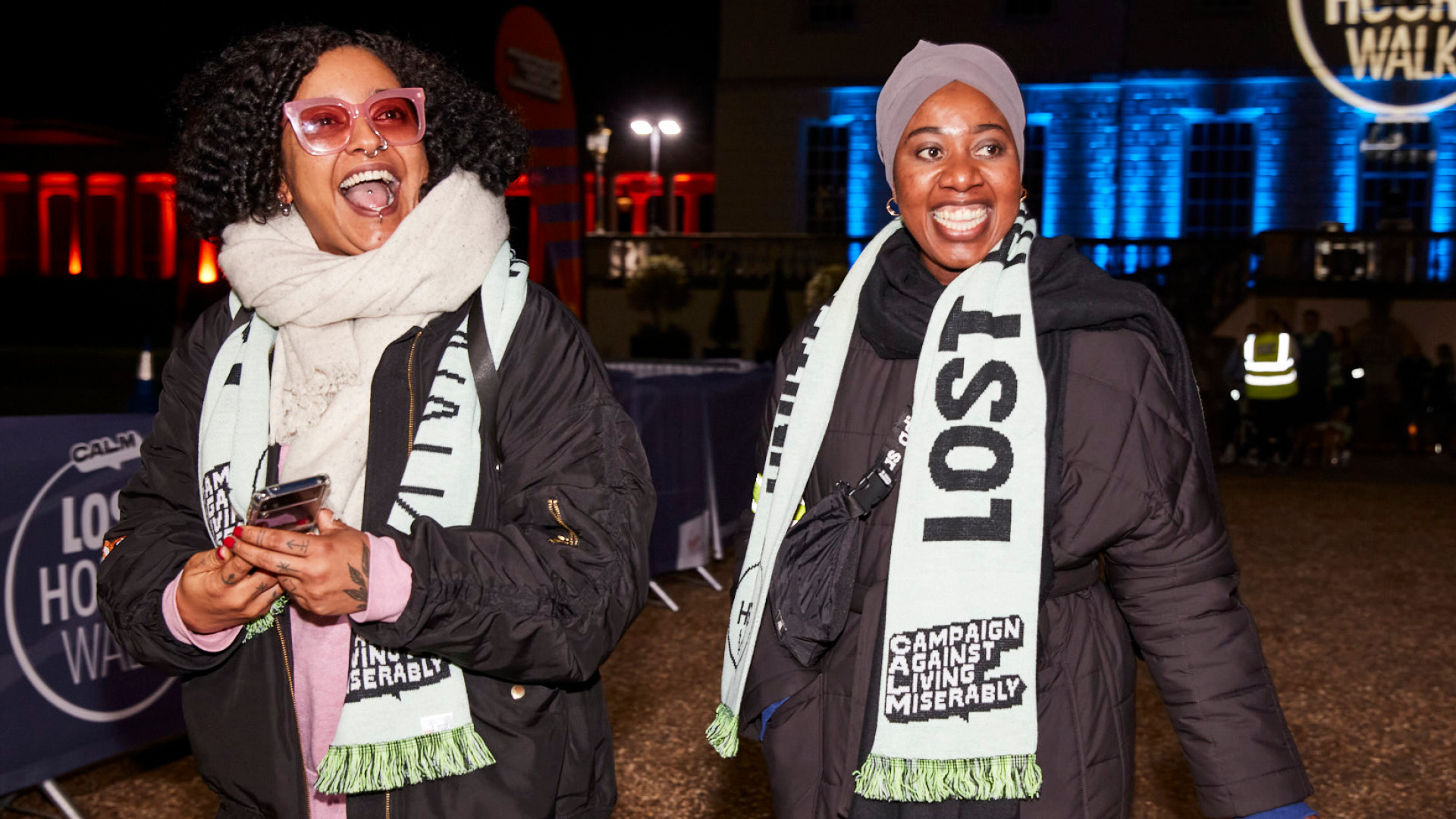 two women smiling while wearing CALM branded scarves