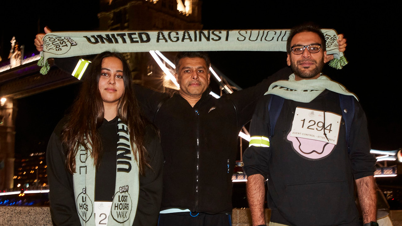3 people standing in front of tower bridge at night, posing with lost hours walk scarves