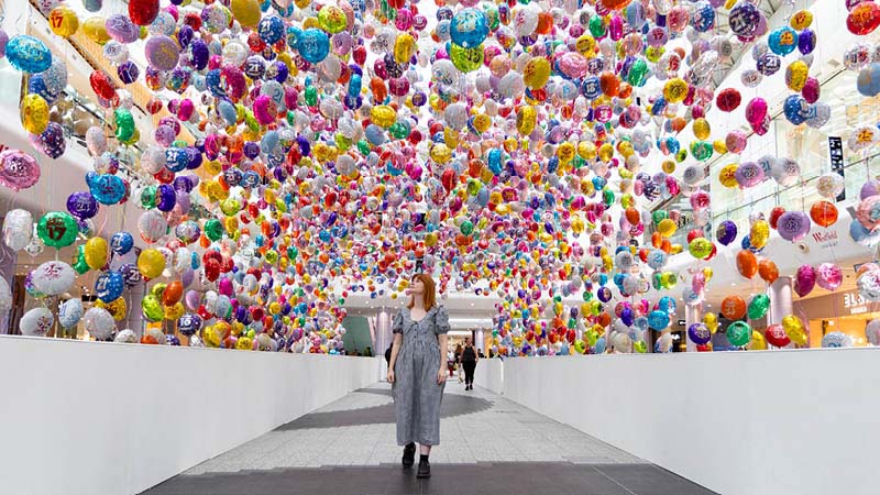A woman looking above at the Missed Birthdays Installation; 6,929 balloons, each one representing a young person who took their own life, and a birthday they didn’t get to celebrate.