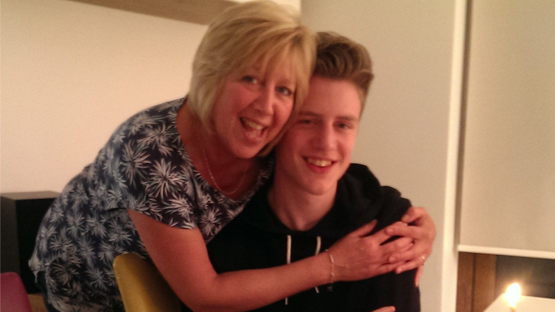 Here we see a photo of Judith leaning over to hug her son, Sam, who is sitting at a table in front of a birthday cake.