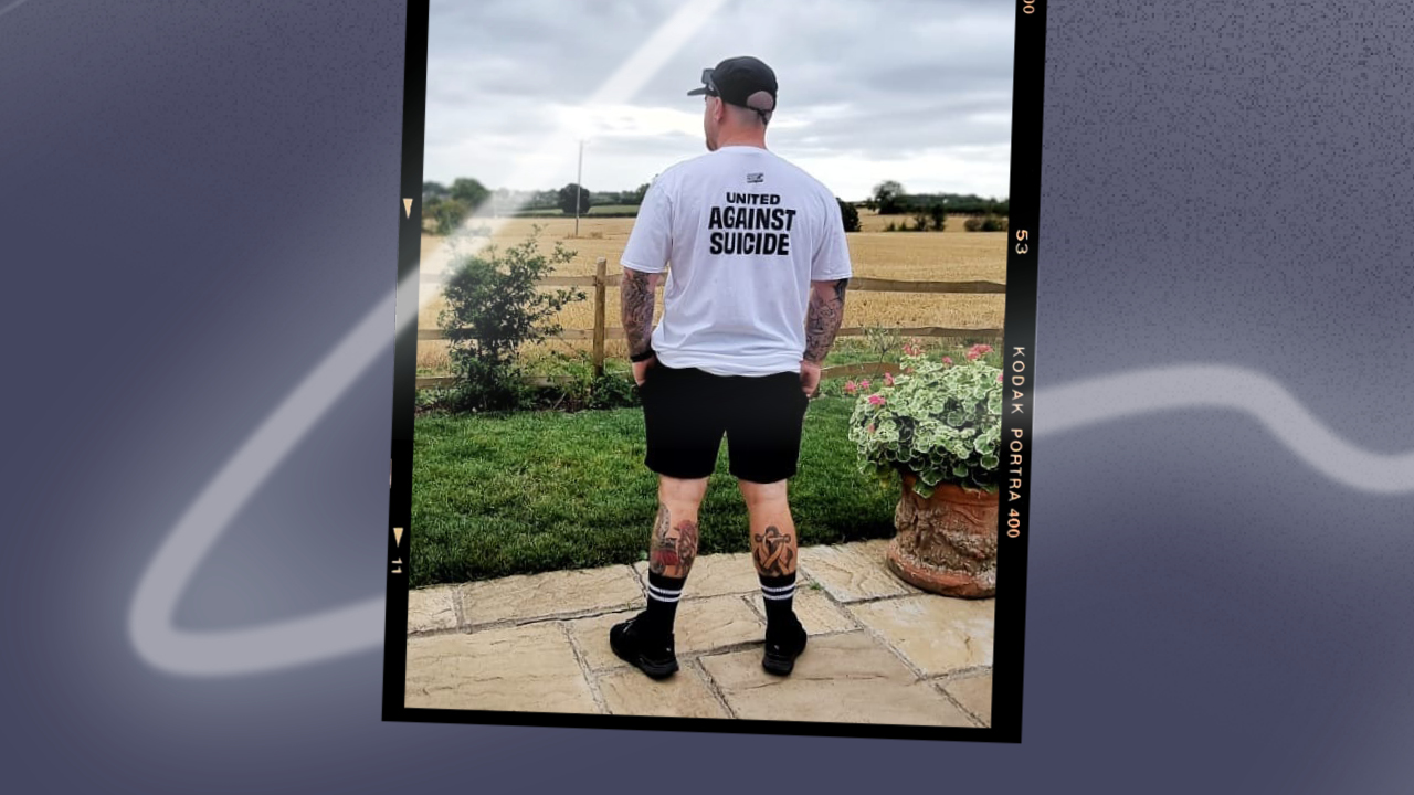 A man standing looking out to a field while wearing a CALM tshirt
