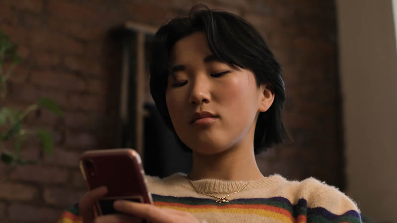 A non-binary person looking at a mobile phone
