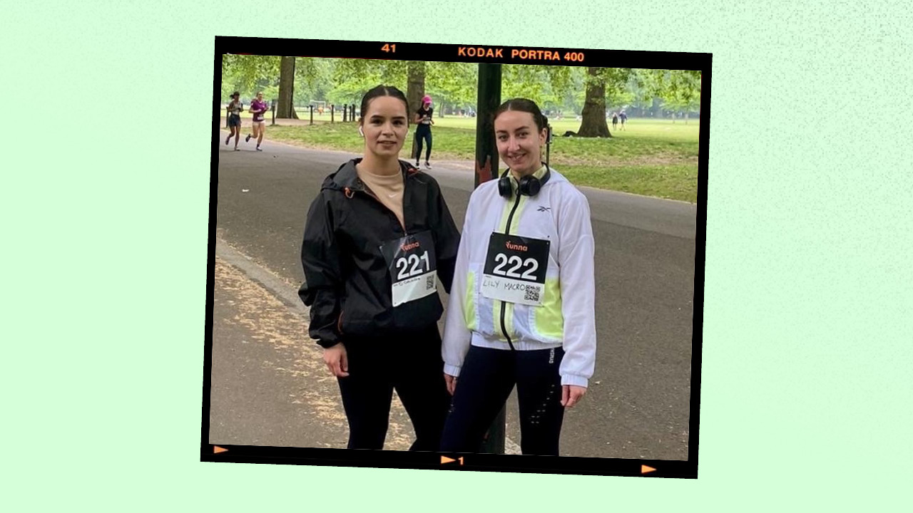 a picture of 2 women standing in a park wearing athletic gear and participant bibs for a race